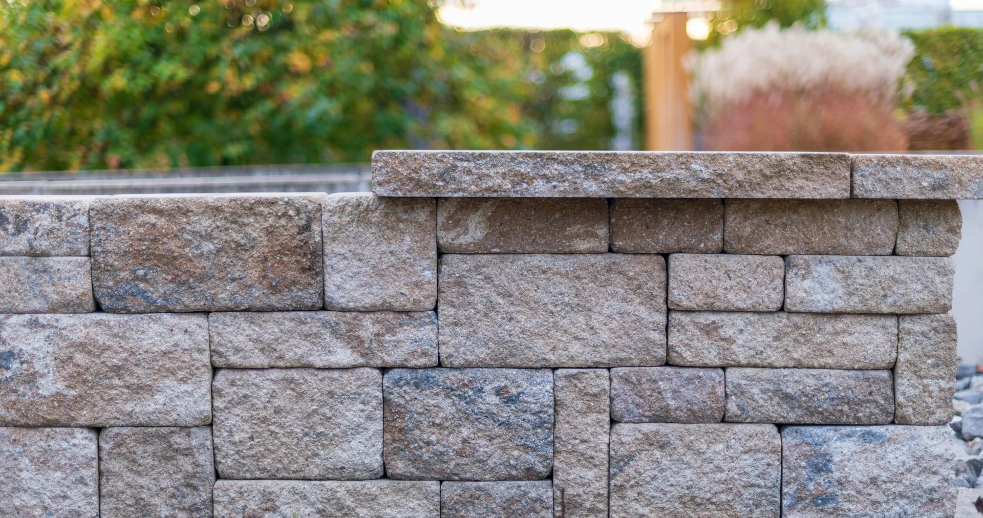 Armour stone retaining wall with a garden and trees above it in Simcoe County
